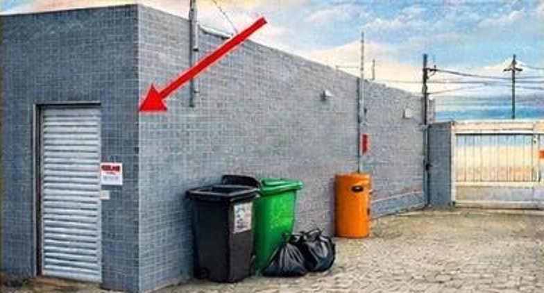 Depósito de lixo coletivo do condomínio, indicado por uma seta, com contêineres ao lado